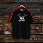 Front view of a Carl Cox motorsport and Team Classic Suzuki black and red t-shirt on a wood background