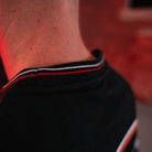 Close up of the neck detailing on a Carl Cox motorsport black t-shirt with an Uggly&Co logo