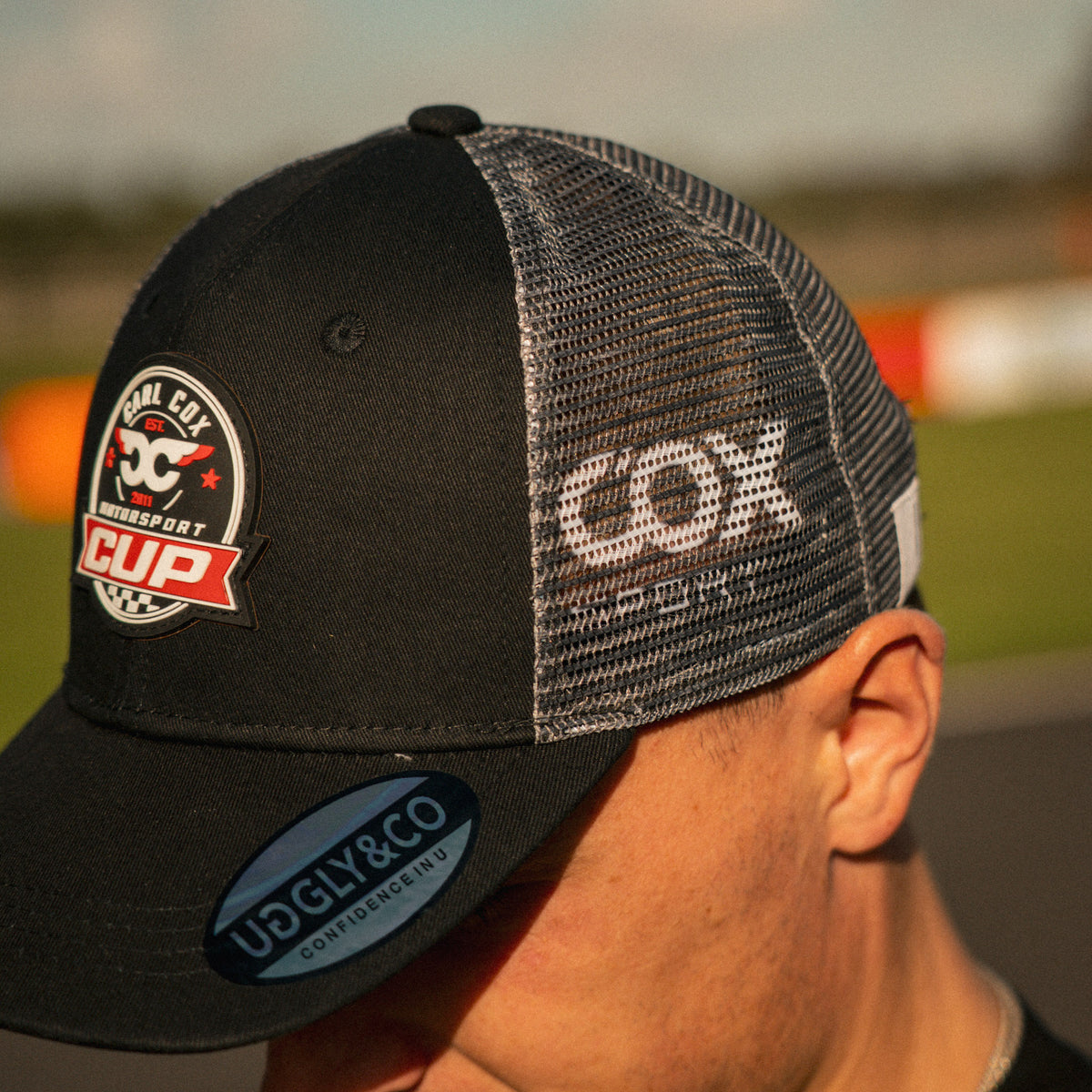 Side profile of the Carl Cox Motorsport Cup Cap, showcasing its curved peak and classic racing cap silhouette from the Uggly & Co motorsport collection.