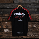 Rear view of a Carl Cox motorsport and Team Classic Suzuki black and red t-shirt on a wood background