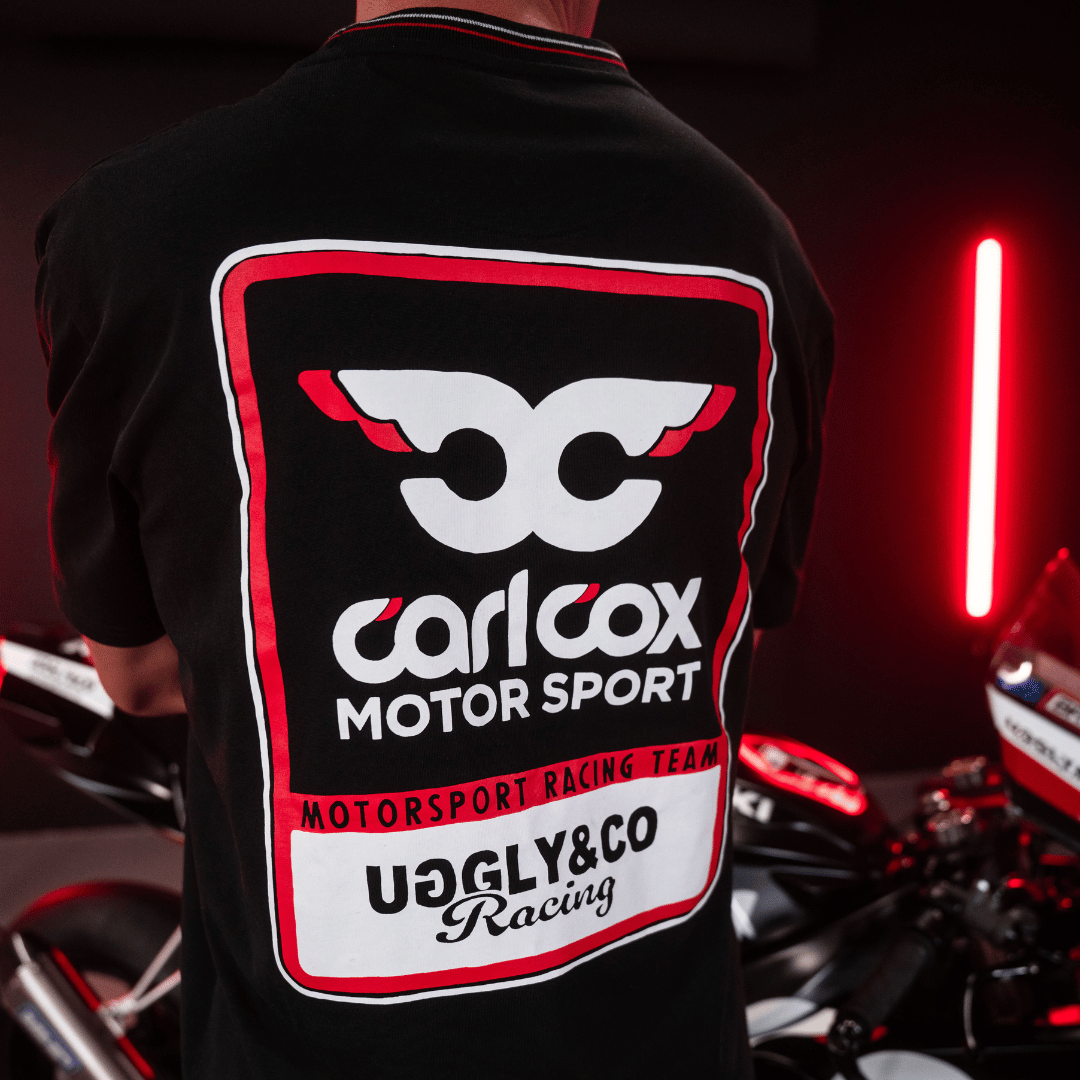 Close up of the detailing on the back of a Carl Cox motorsport black t-shirt with an Uggly&Co logo and a motorcycle behind