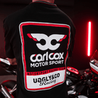 Close up of the detailing on the back of a Carl Cox motorsport black t-shirt with an Uggly&Co logo and a motorcycle behind