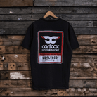 Rear view of a Carl Cox motorsport black t-shirt with an Uggly&Co logo on a wooden background