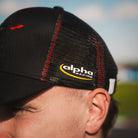Side profile of the Carl Cox x Alpha Racing & Simon Reid Trucker Hat, showcasing its alpha racing logo