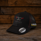 Carl Cox Trucker Hat x Alpha Racing & Simon Reid shown from the front with black panels, motorsport branding and a classic trucker fit.