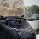 Girl model wearing a beige knitted Diamond beanie beside the pit lane