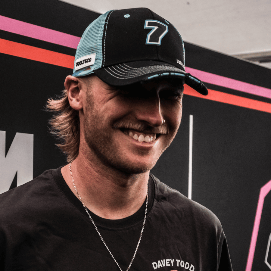 Davey Todd smiling while wearing an official Davey Todd Merchandise black and blue trucker hat with the number 7 and the text 'UGGLY&CO' on the front