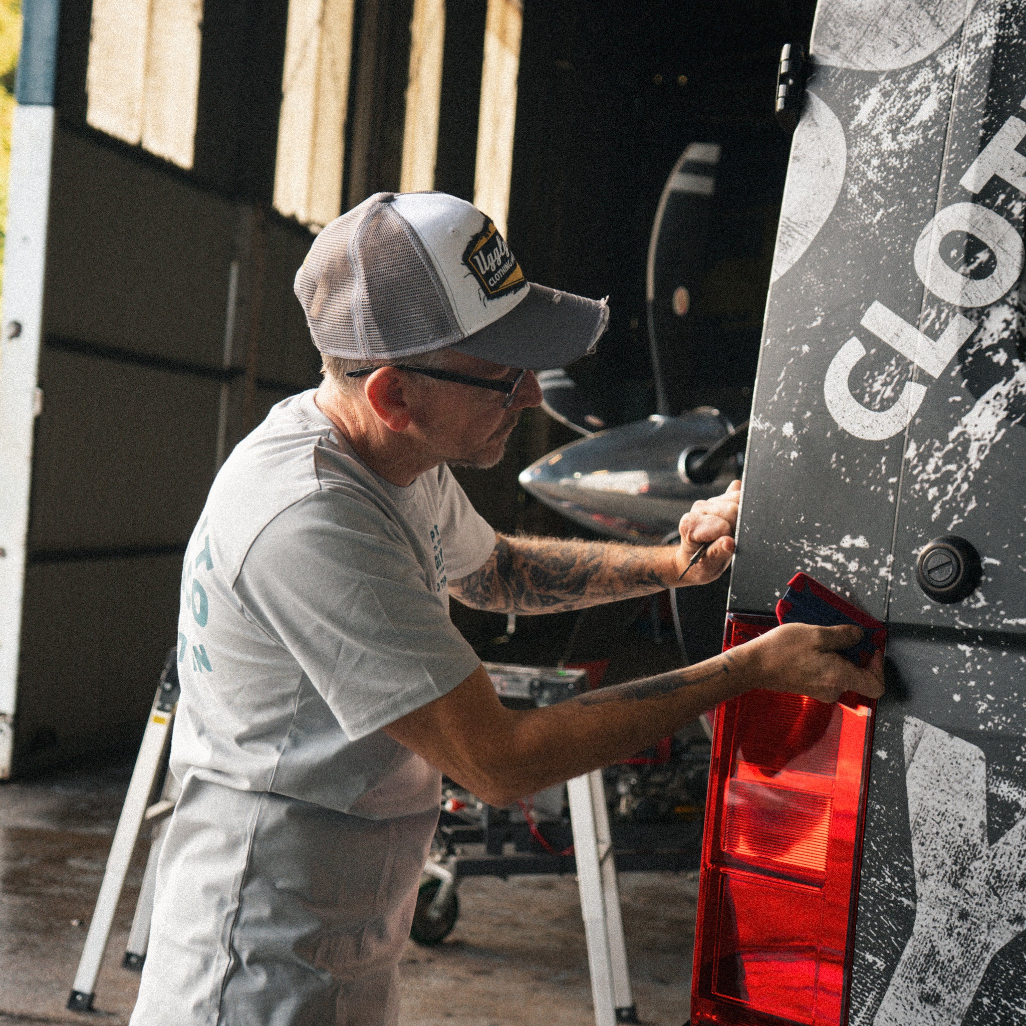 Grey & White Diamond Trucker Cap worn during a van wrapping session inside a hangar.