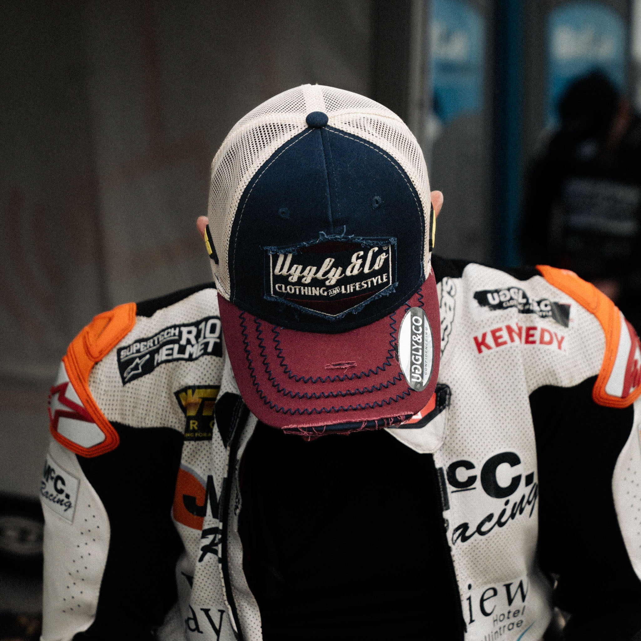Jeremy McWilliams in red, white and blue trucker hat stood in pit lane with head down