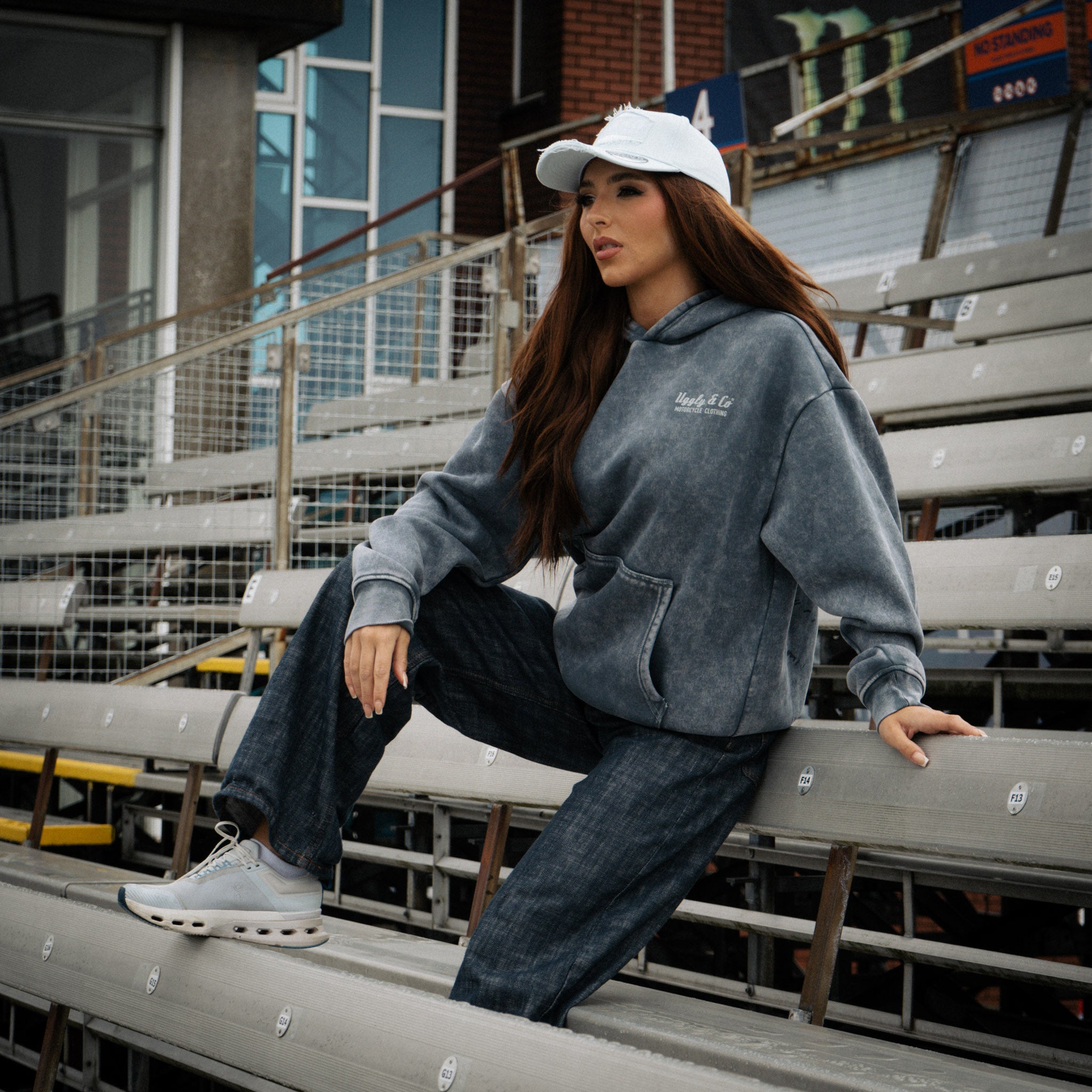 Female model wearing a blue acid wash hoodie in a casual lifestyle setting.