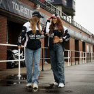 Female models wearing a Carl Cox Motorsport track jacket at a motorsport event.