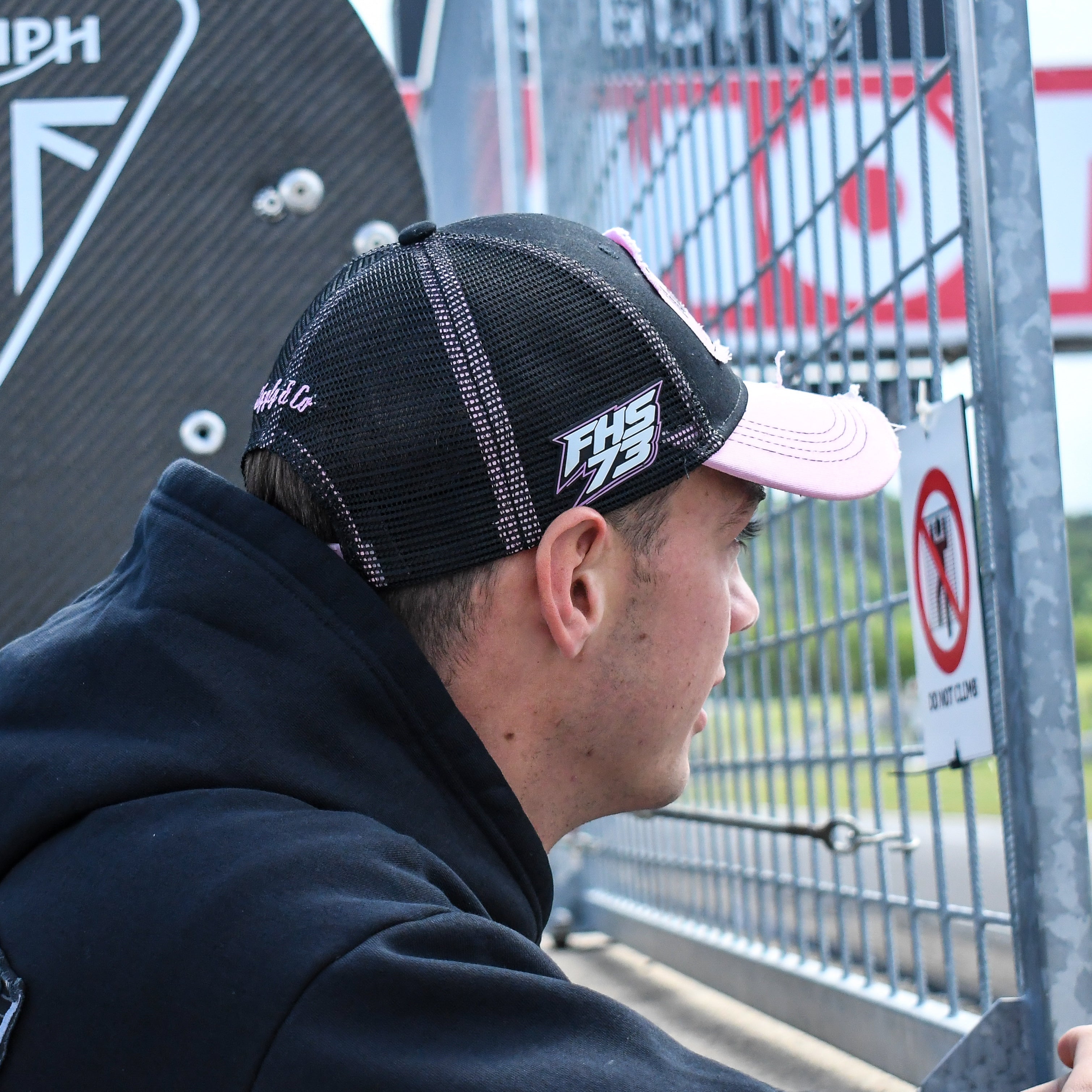Close up side-profile image of Fenton Seabright in a black and pink trucker cap during race day preparations