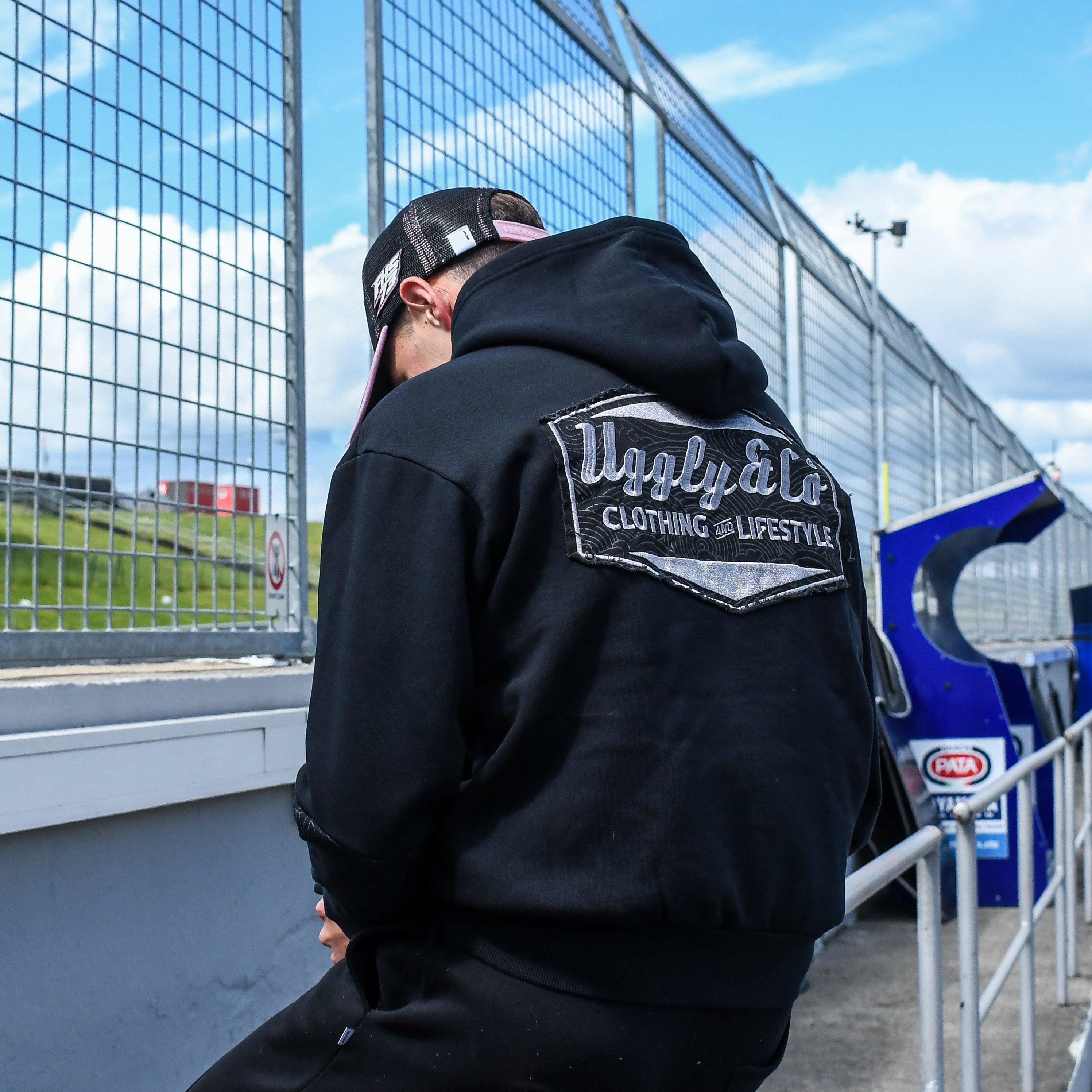 Rear view of Fenton Seabright sat on railing at racetrack