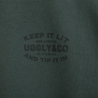 close up product photo of the uggly and co green keep it lit t shirt