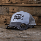 Grey and white trucker hat with an Uggly&Co logo on a wooden background