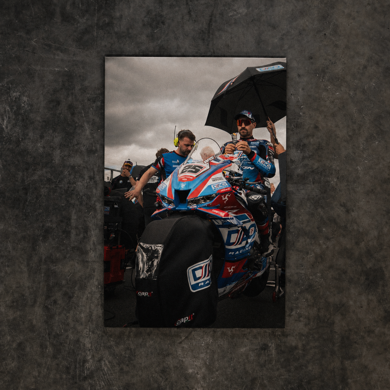 Josh Brookes sitting on the number 25 DAO Racing motorcycle on the British Superbike Championship grid beneath a race umbrella.