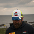 Jamie Coward showing trucker hat with head down near the beach