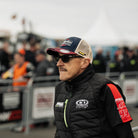 Jeremy McWilliams in the pit lane, stood wearing a hat and sunglasses on racetrack grid