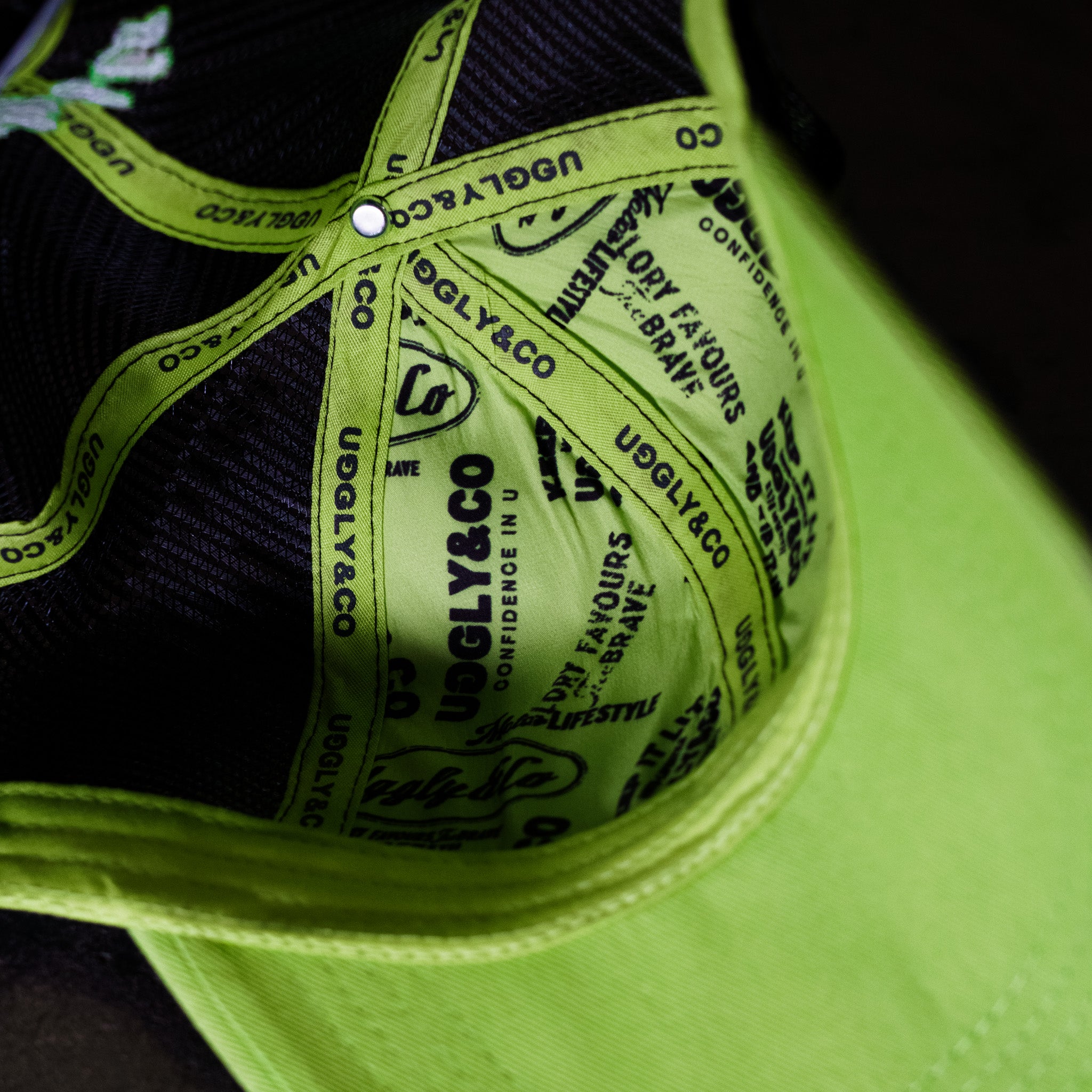 Inside view of the Uggly & Co Fluro Diamond Trucker Hat x Kyle Ryde on a concrete floor, showcasing the inner lining and construction of the British Superbikes cap.