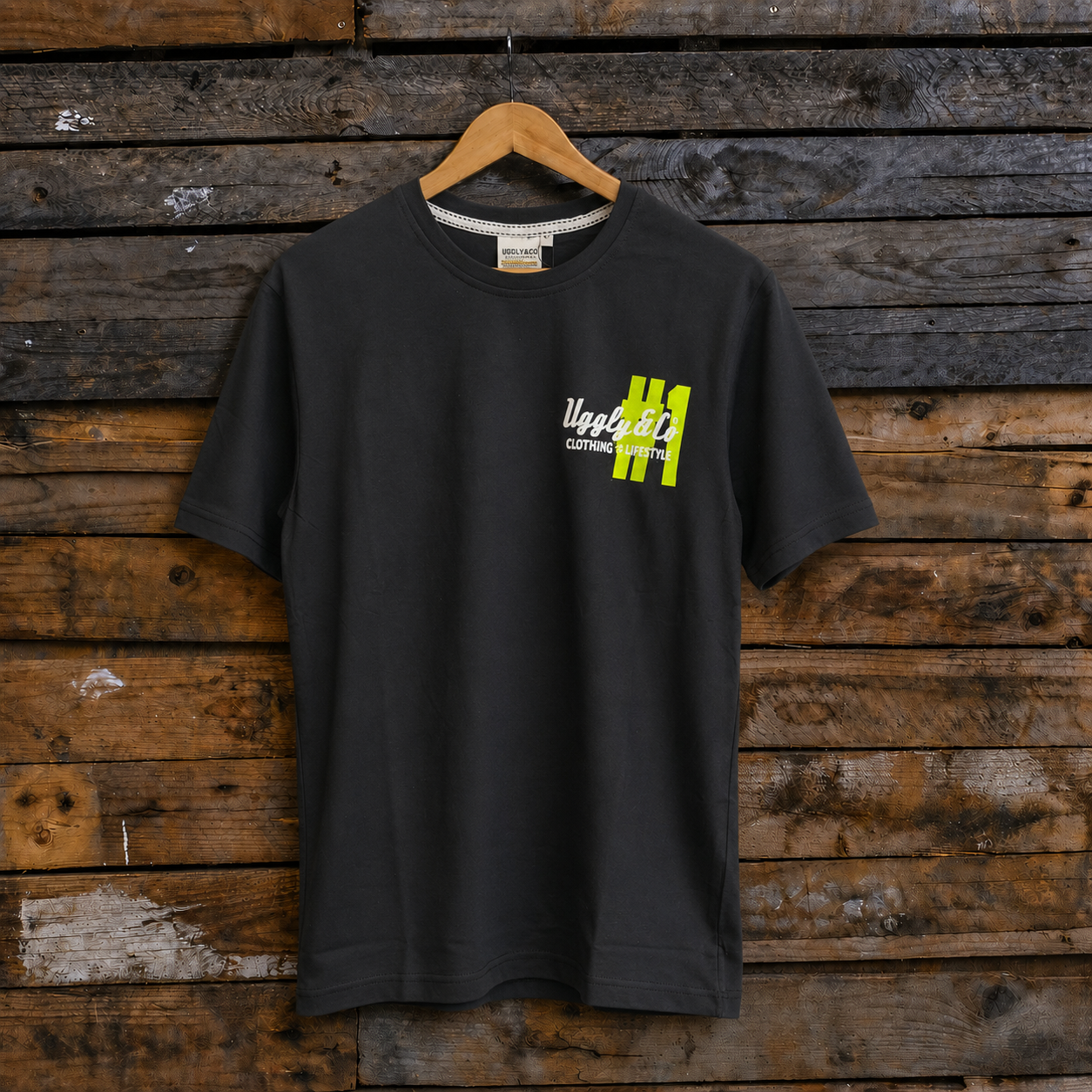 Front view of an Uggly & Co and Kyle Ryde #1 diamond graphic black t-shirt with white and lime green accents on a wooden background