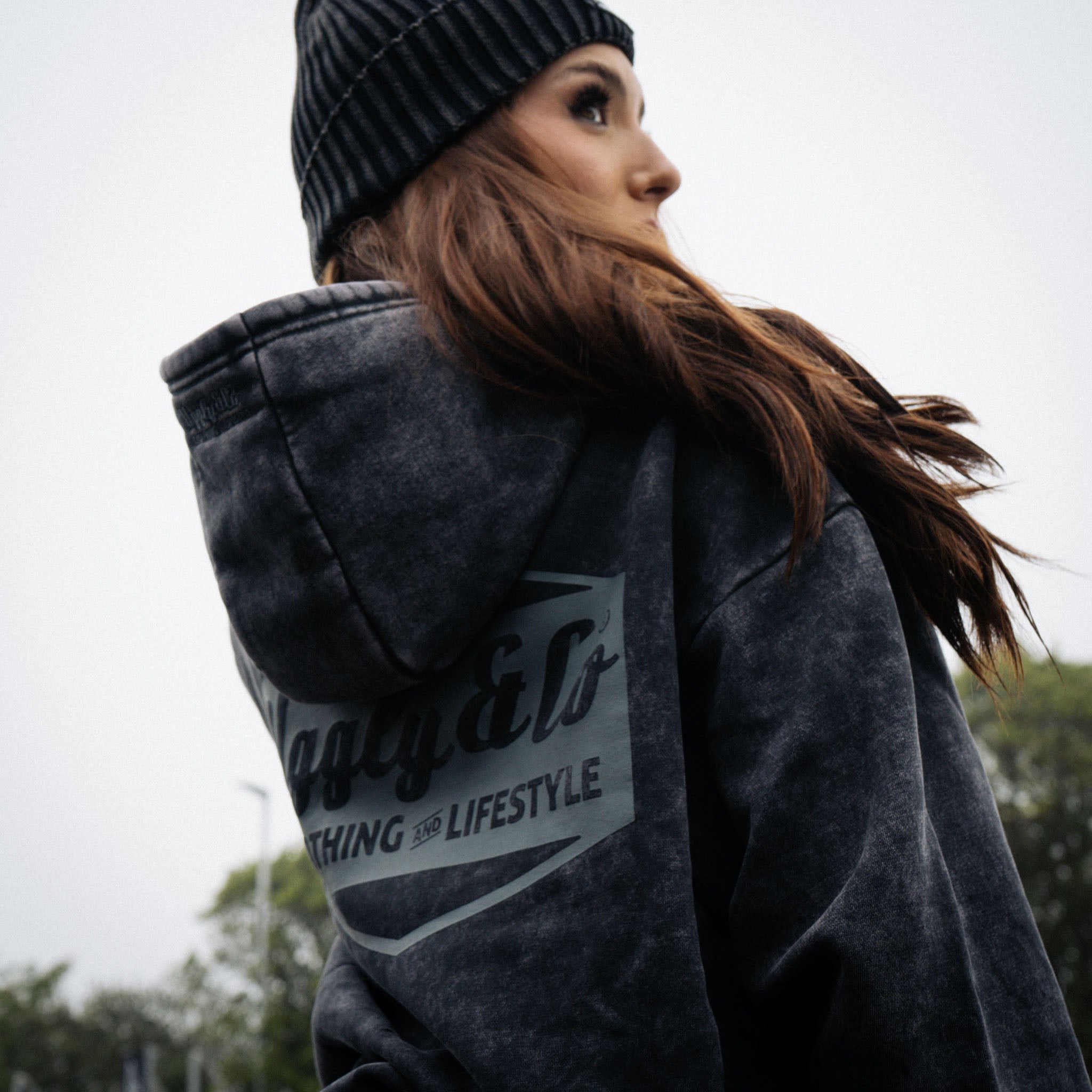 Black Diamond beanie worn by a female model in a motorsport pit lane setting