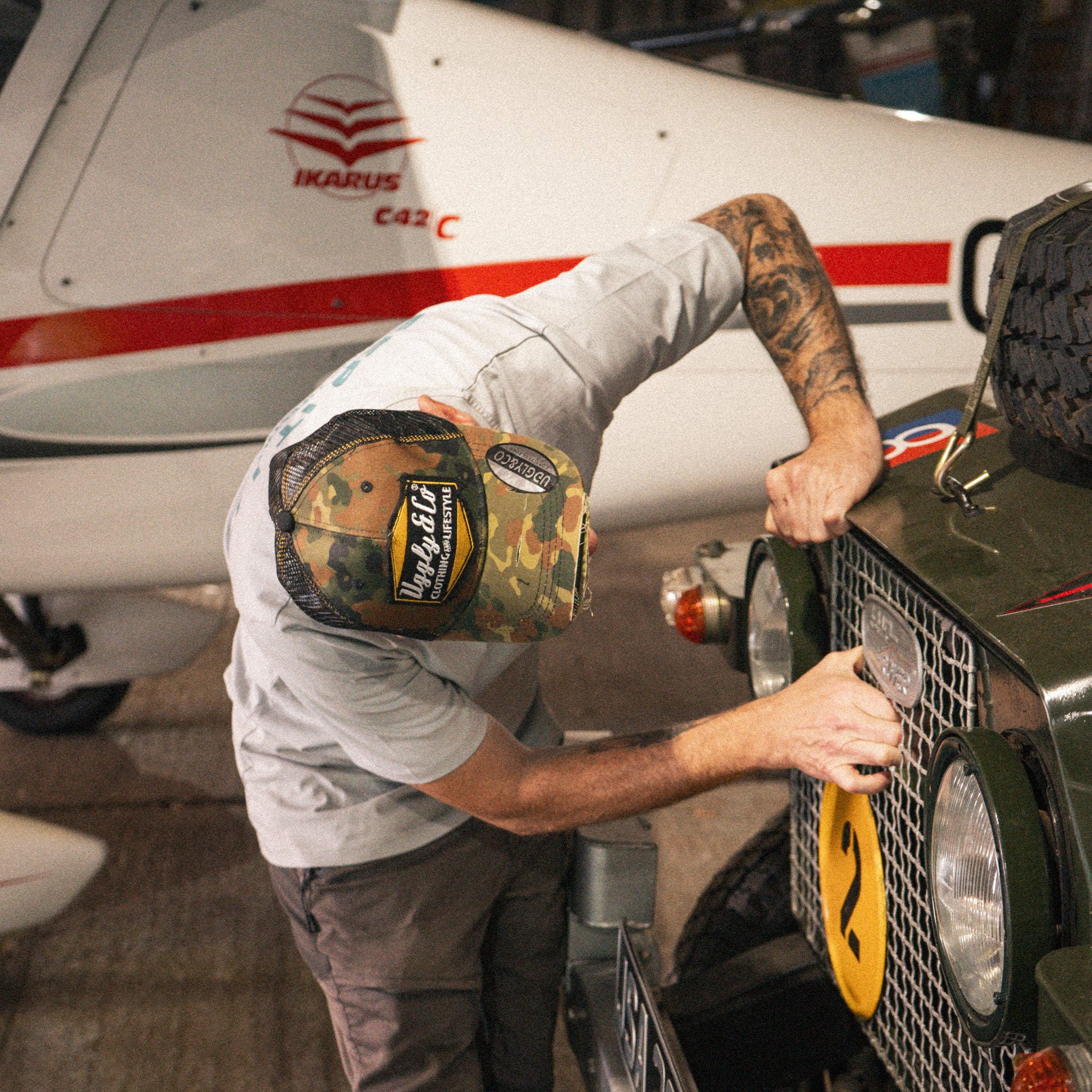 Mens Green Camo Diamond Trucker Hat styled with workwear while repairing a Land Rover.