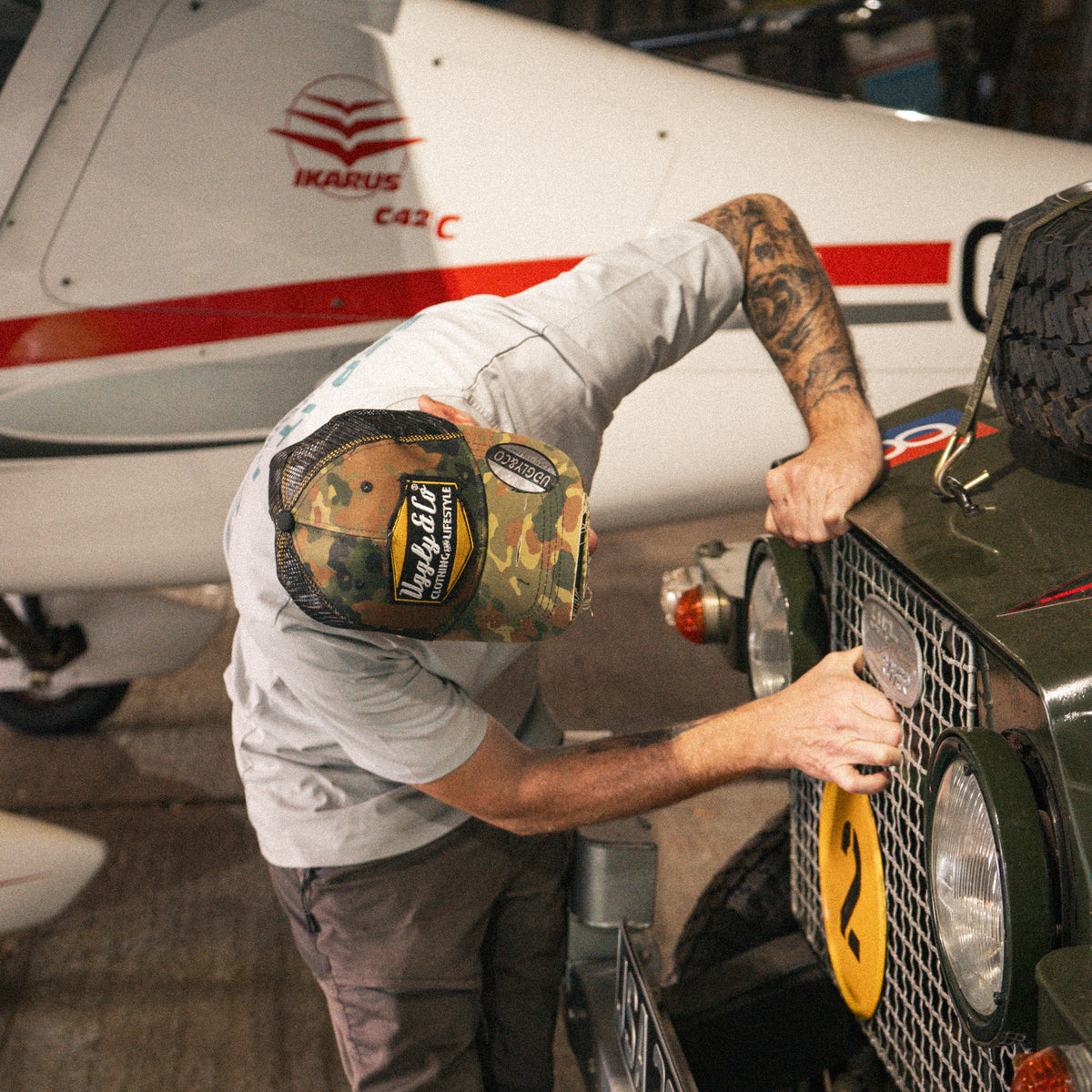 Mens Green Camo Diamond Trucker Hat styled with workwear while repairing a Land Rover.