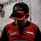 Person wearing a red and black cap with a brick wall background