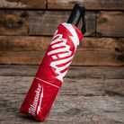 A Milwaukee Tools x Ducati umbrella in the packing sleeve with red and white accents on a wooden backdrop