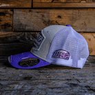 Side view of a white and purple trucker hat with Uggly&Co diamond logo on the front, a mesh back and Mitch Rees Racing logo on the side