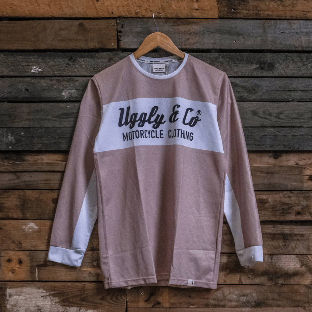 Brown long-sleeve motocross jersey with 'Uggly & Co Motorcycle Clothing' logo on a wooden background