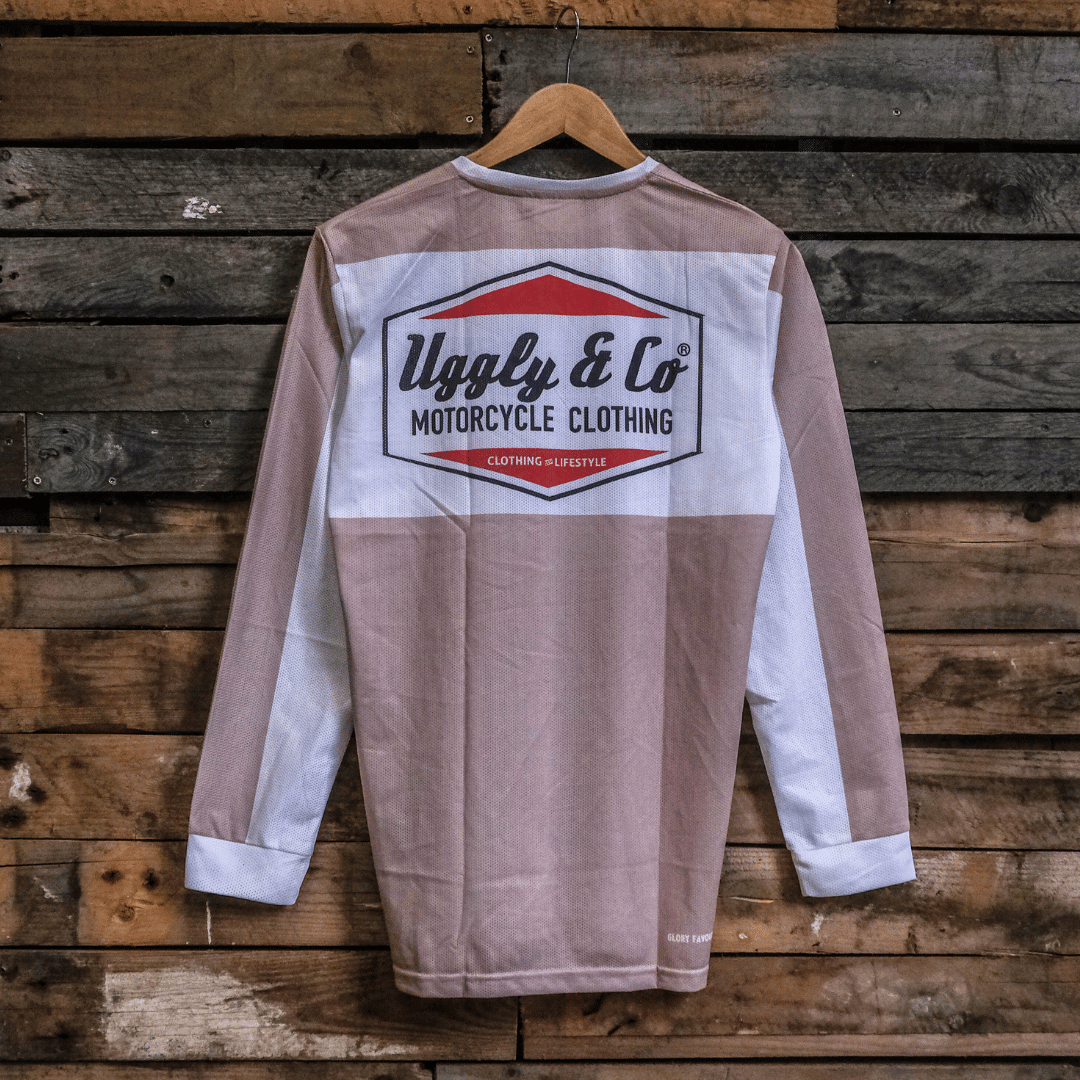 Long-sleeve motocross jersey with 'Uggly & Co Motorcycle Clothing' logo on a wooden background