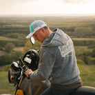 Motorcyclist in a turquoise and white trucker hat with a Royal Enfield Scram 411 scrambler