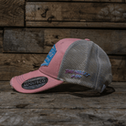 Pink and gray cap with mesh back on a wooden surface