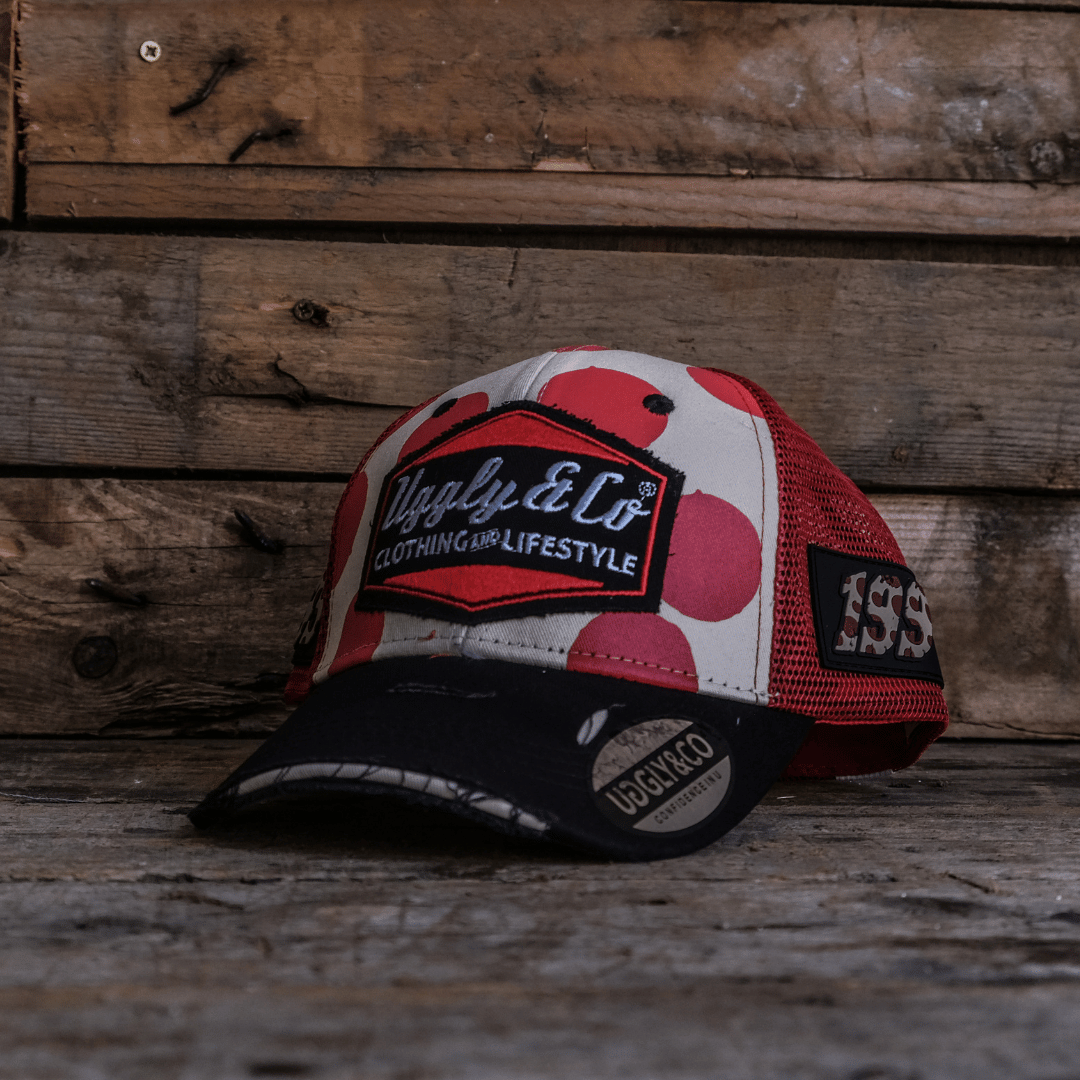Trucker hat with red and white polka dot design and signature Uggly&Co logo on a wooden background