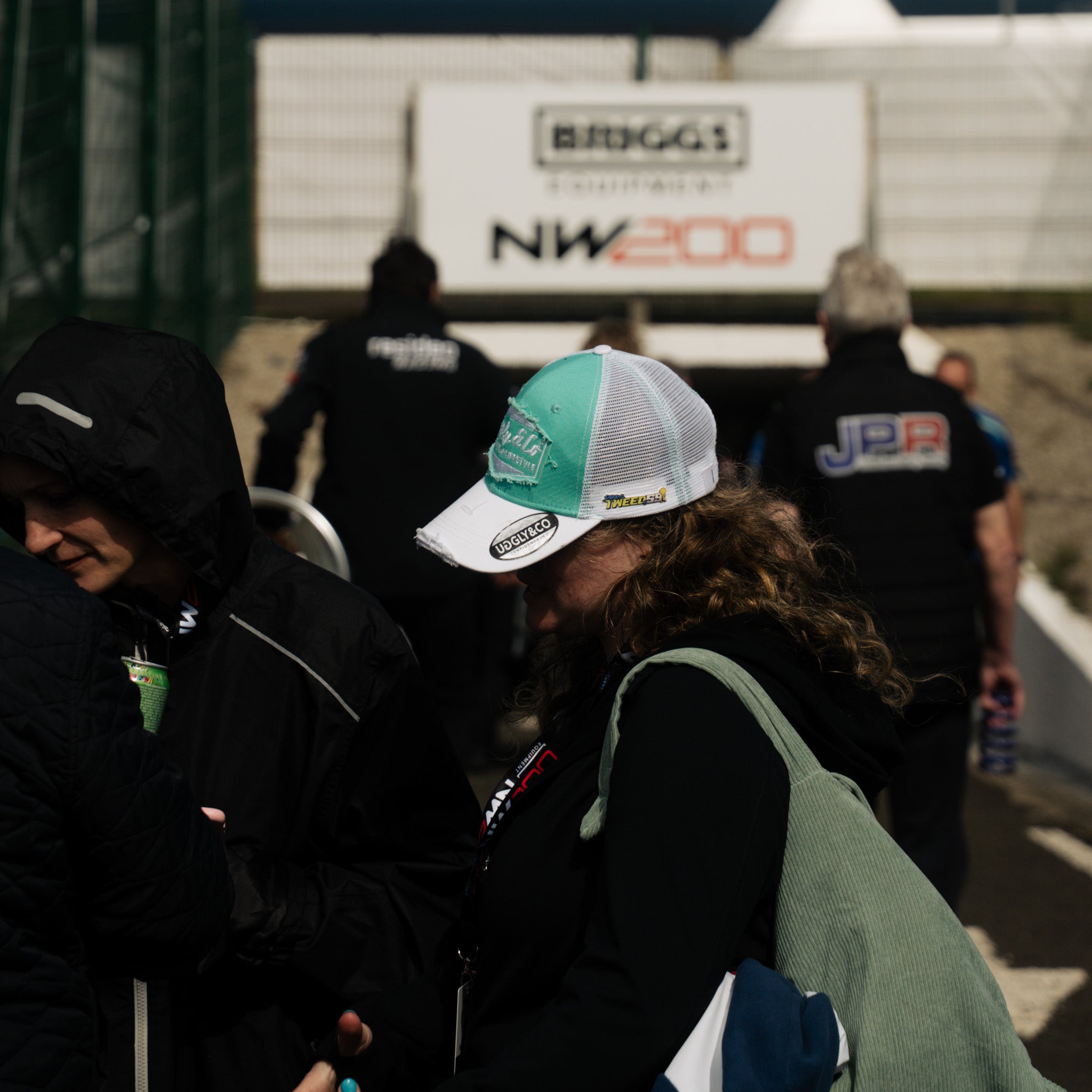 Race fan wearing turquoise hat in tunnel to a racetrack