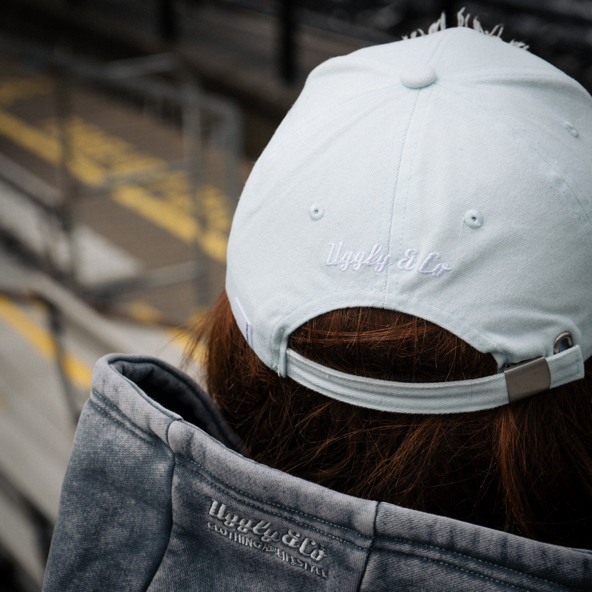 close up rear view shot of a girl wearing a blue cap at a motorsport race