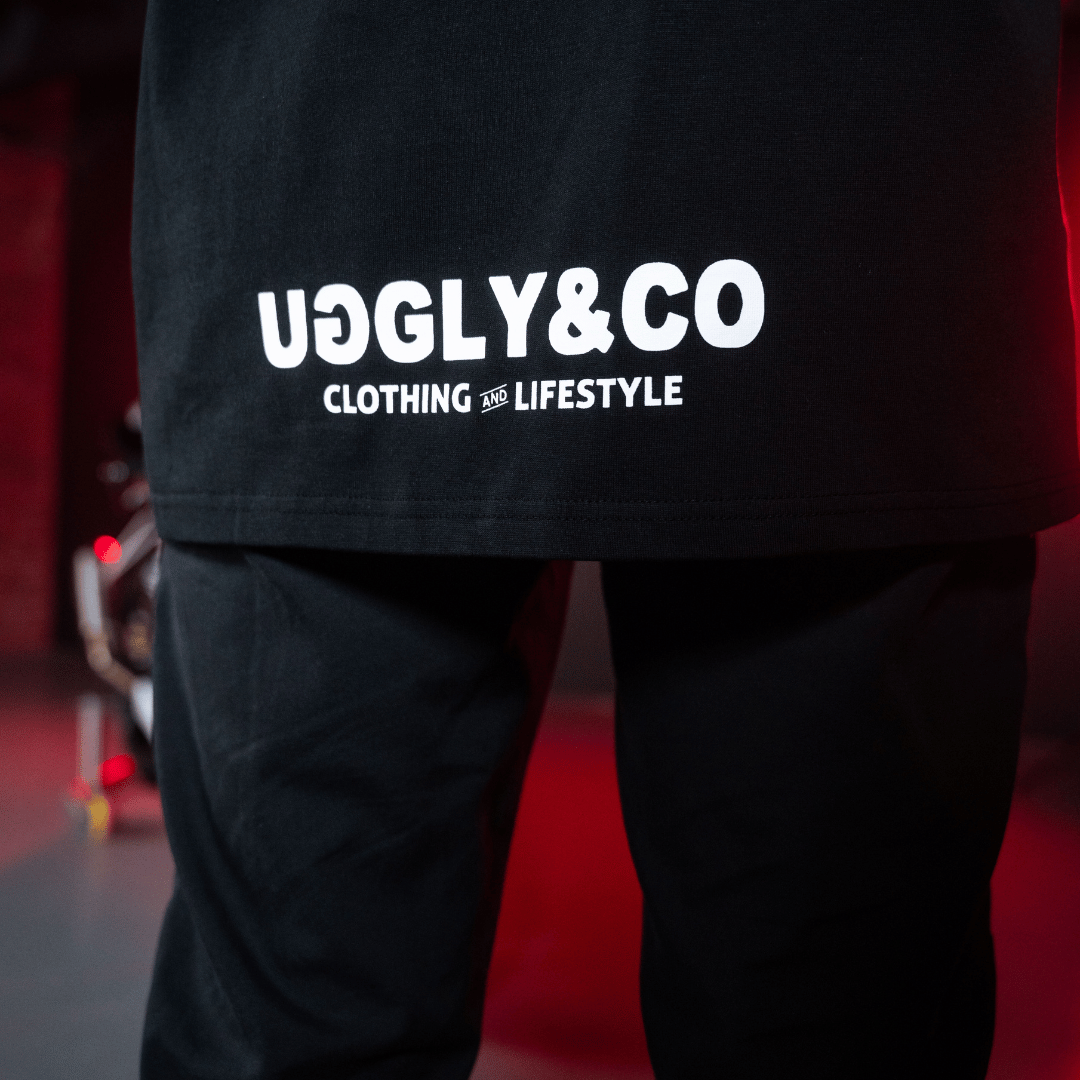Close up of the Uggly&Co logos on the bottom of the back of a Carl Cox motorsport and Team Classic Suzuki black and red t-shirt