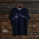 Front view of a navy Team Classic Suzuki blue t-shirt with Uggly&Co branding on a wooden background