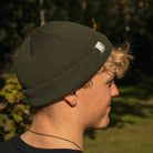 Close-up of the logo detail on the Olive Fisherman Beanie worn by Rhys Irwin