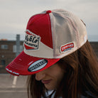 Lifestyle photo of a female model wearing the Smokin’ Diamond Trucker Hat. Marlboro inspired  cap.