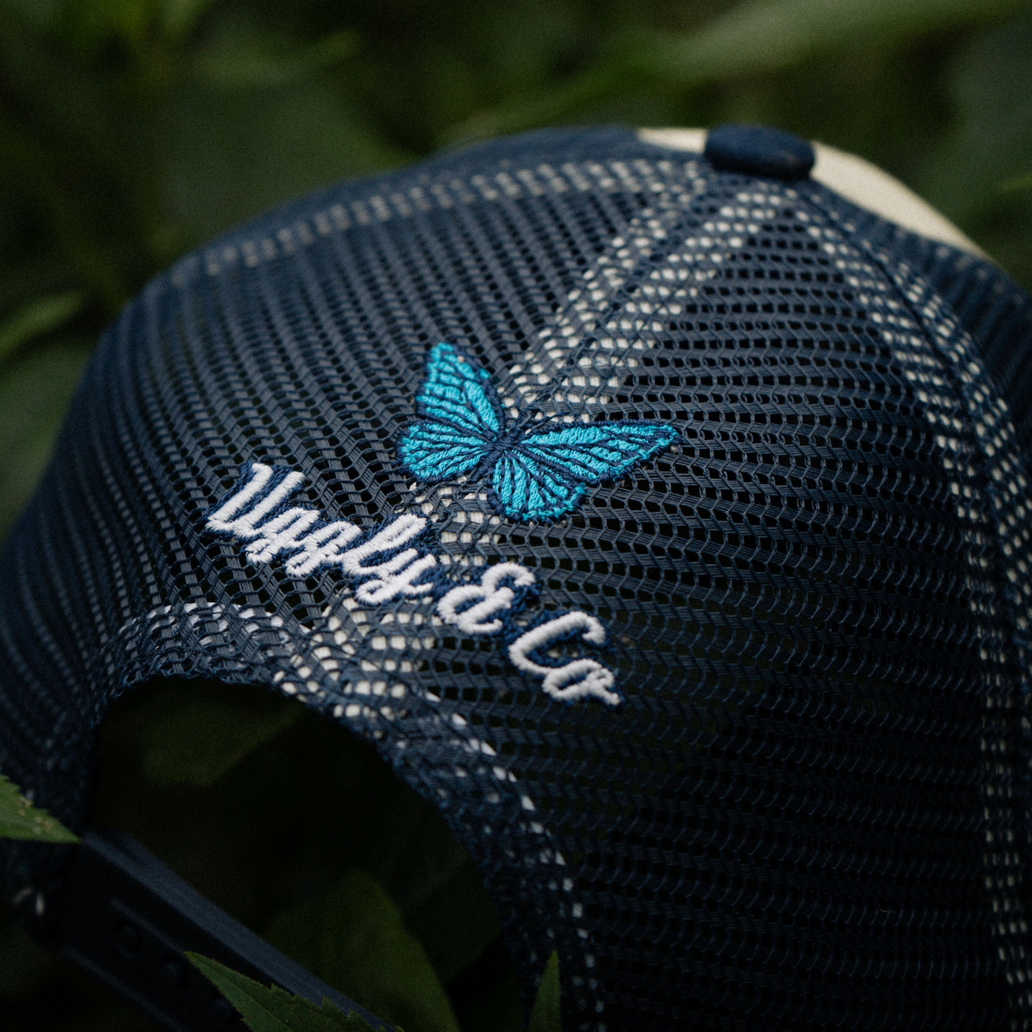 Rear view of charity hat with butterfly, shot in green plants