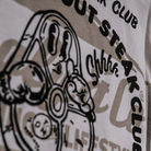 Close up of the rear logo on a Tom Kerridge's Butchers Tap and Grill white t-shirt with black graphics and text