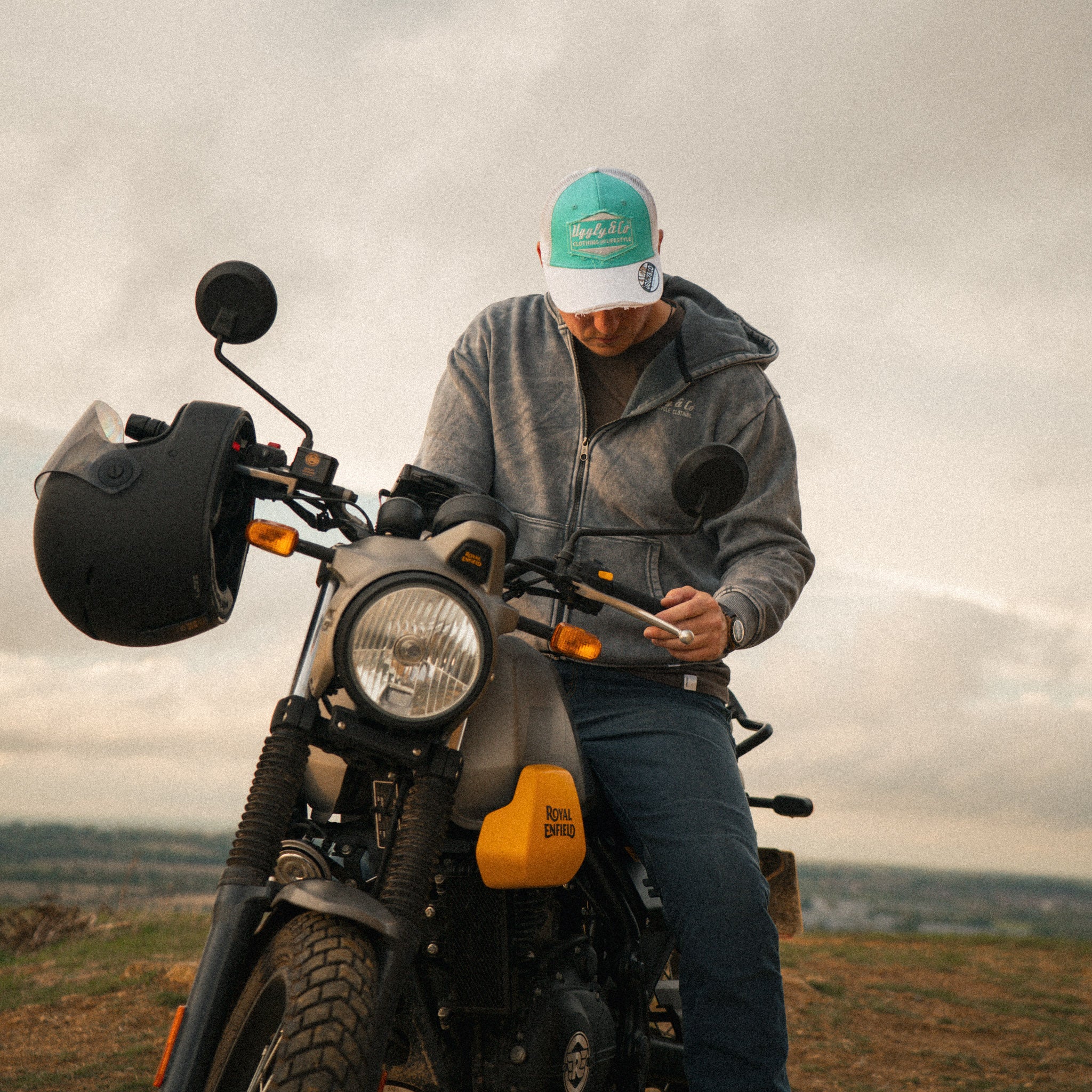 Rider wearing the Uggly&Co Turquoise & White Diamond Trucker Hat, sitting on a Royal Enfield Scram 411