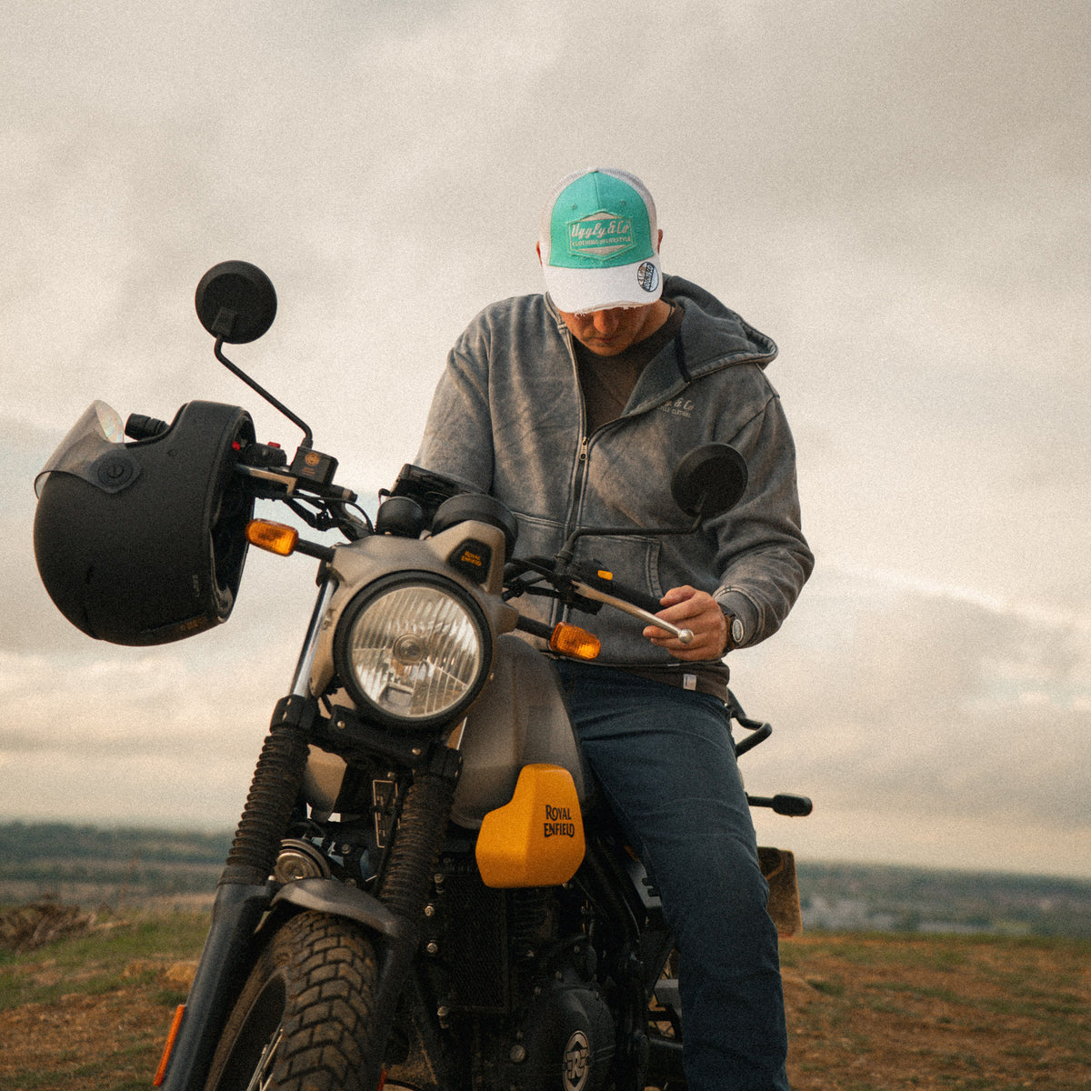Rider wearing the Uggly&Co Turquoise & White Diamond Trucker Hat, sitting on a Royal Enfield Scram 411