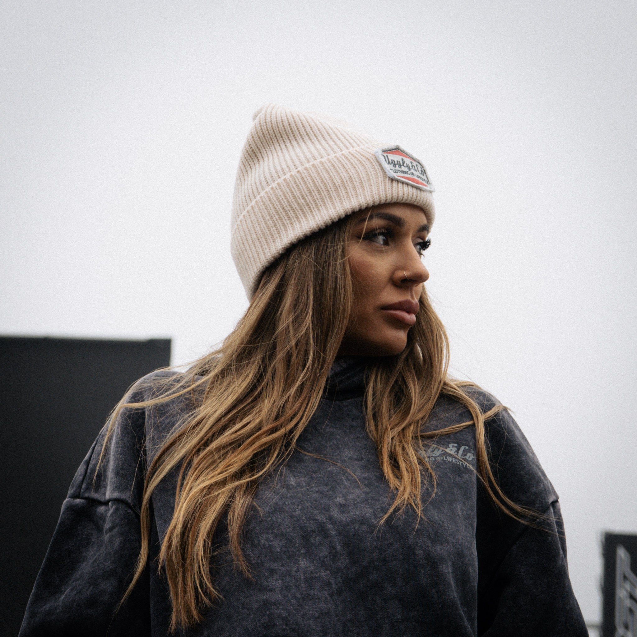 Female model wearing the Uggly&Co beige Diamond Beanie at a road racing event