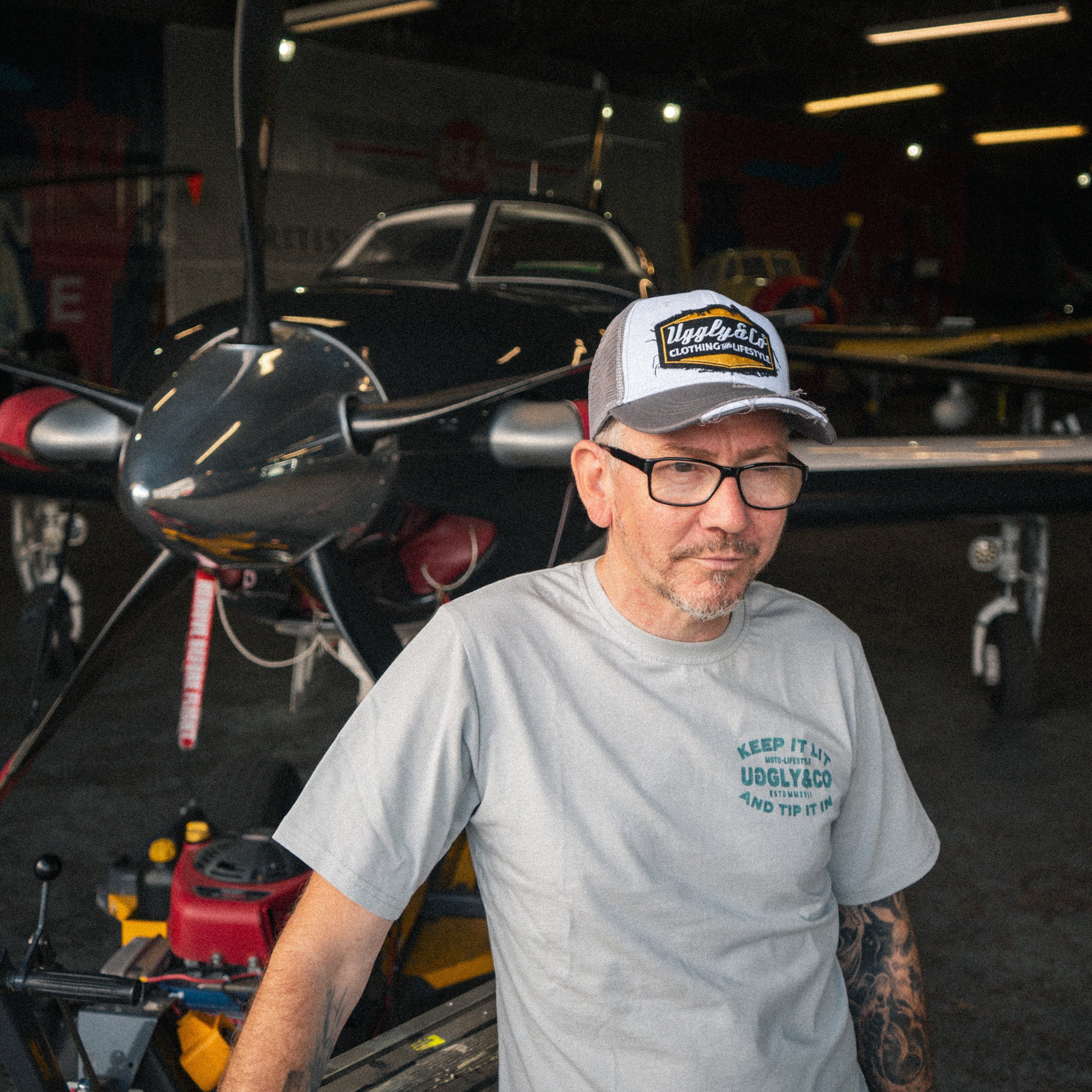 Uggly & Co Diamond Trucker Cap worn by a man wrapping a van in a large aircraft hangar.