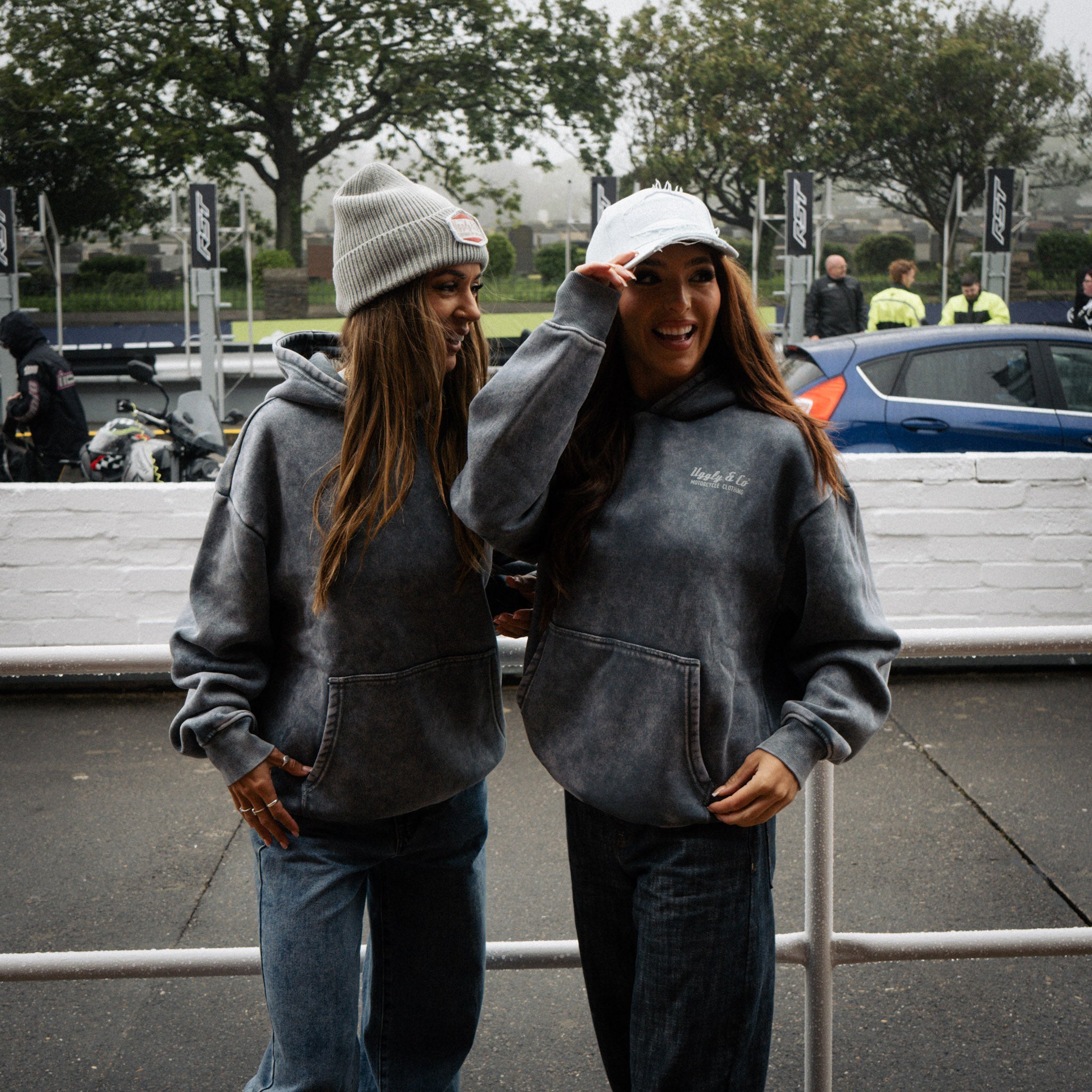 Female models wearing the Uggly&Co Grey Diamond Beanie and arctic diamond cap at a road racing event