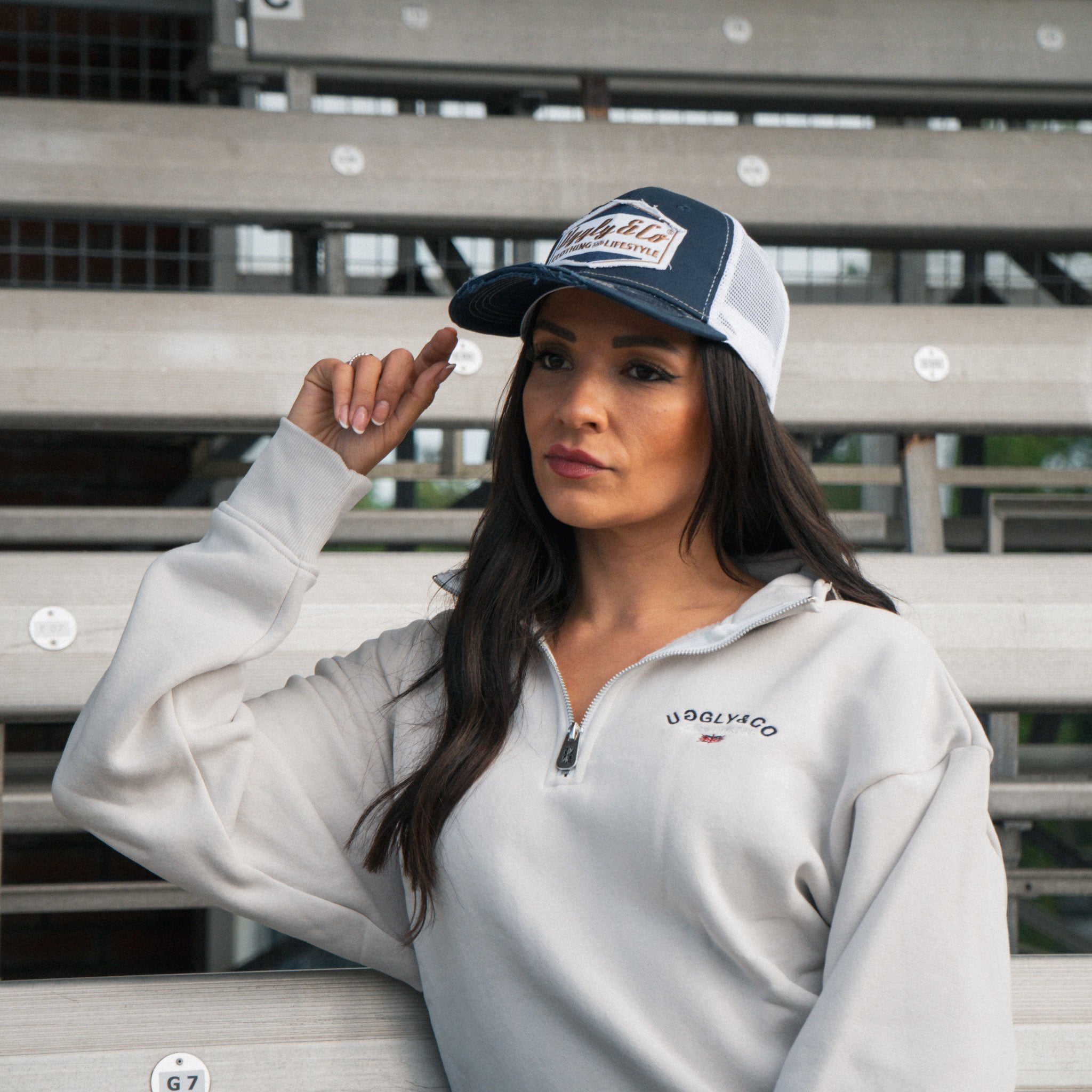 Female model wearing the Uggly&Co Night Blue and Gold Diamond Cap in the grandstand at a race event