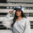 Female model wearing the Uggly&Co Night Blue and Gold Diamond Cap in the grandstand at a race event